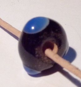 schmale schwarze Perle mit drei weiß-blauen Augen