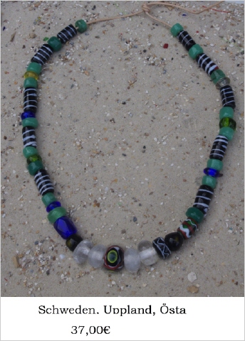 Eine Glasperlenkette mit 4 Bergkristal, einigen grünen und blauen sowie zehn tonnenförmigen schwarzen Perlen mit weißer Spiralfadenwicklung